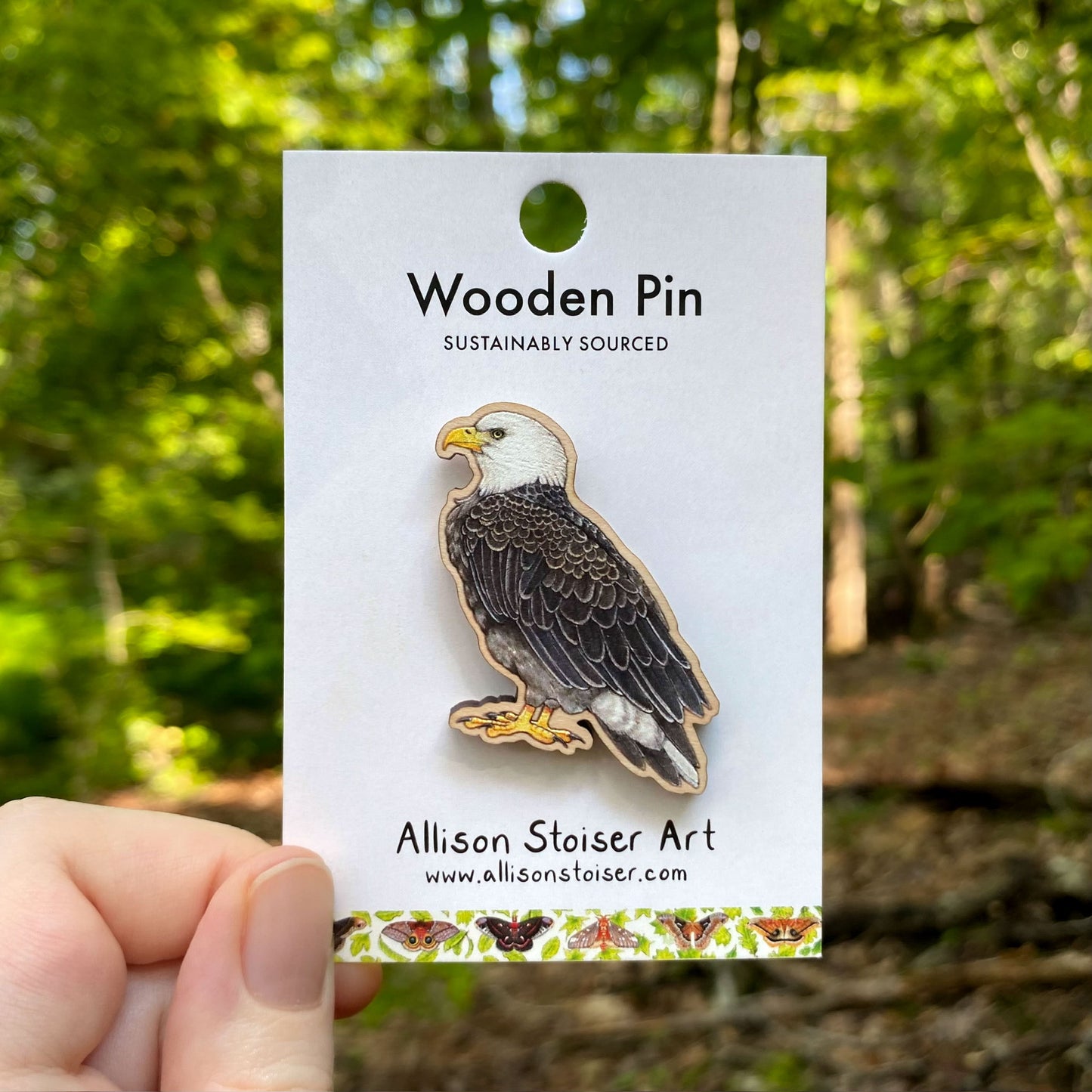 Wooden pin of a bald eagle on a card with a forest background