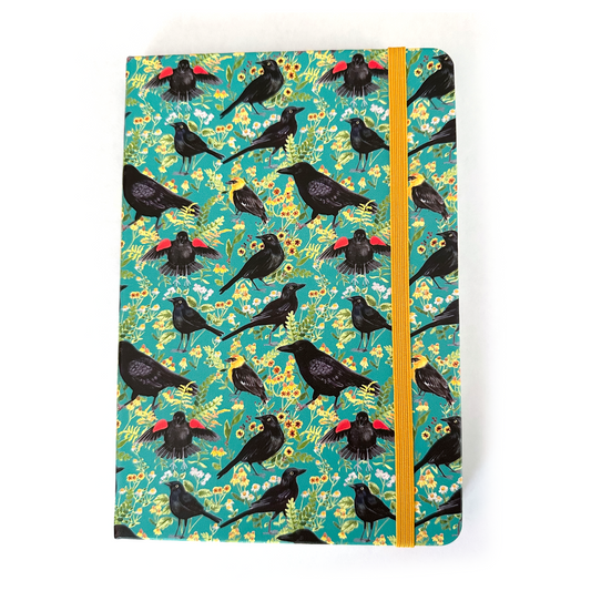 Notebook with black bird and flower pattern on a teal background