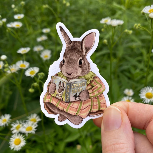 Sticker of a rabbit holding a book in a field with flowers. The book's title is Jane Hare.