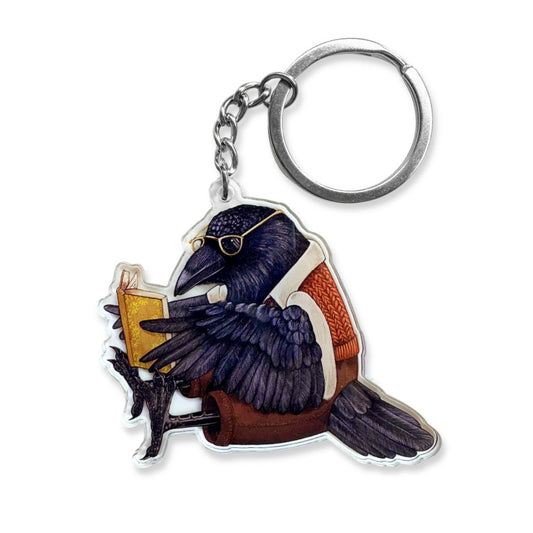 A keychain of a raven reading a book.
