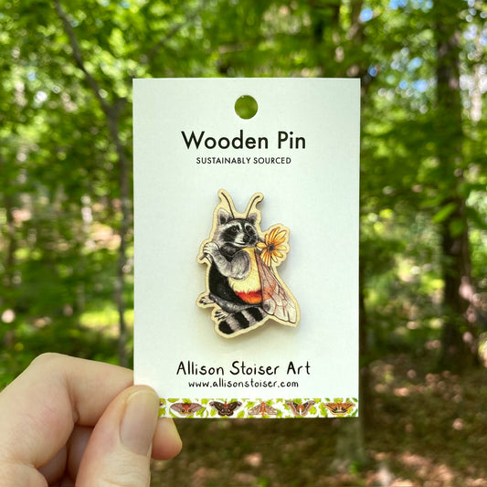 A wooden pin of a Raccoon dressed as a bumblebee