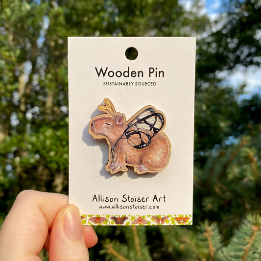 A wooden pin of a capybara with butterfly wings