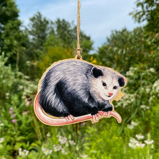 A wooden ornament strung with twine of a Virginia opossum.