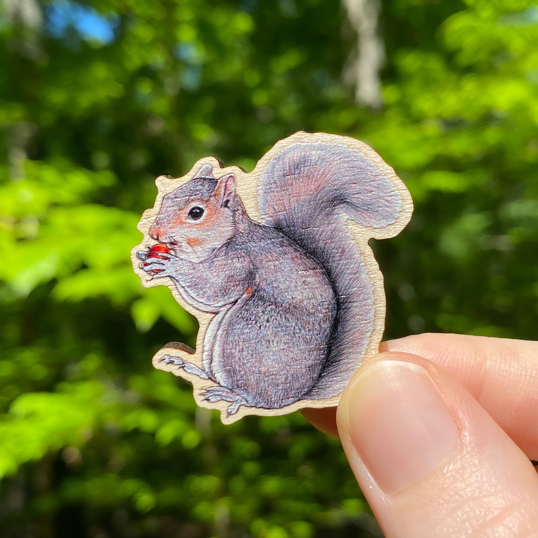 A wooden pin of an eastern gray squirrel on a white background.