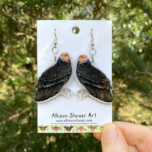 A hand holding a pair of California Condor acrylic earrings