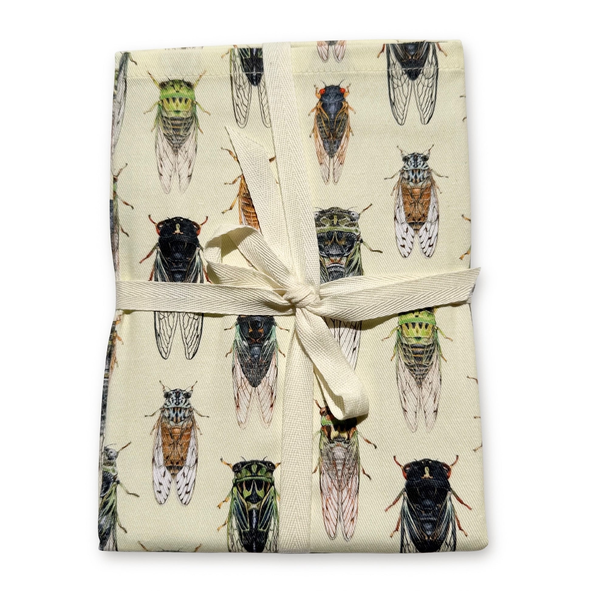 A folded cream-colored tea towel featuring a repeating pattern of detailed cicada illustrations, tied with a cream ribbon bow on a white background.