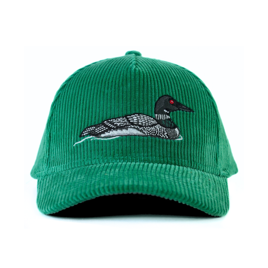 The front of a green corduroy baseball cap with an embroidered common loon on a white background.