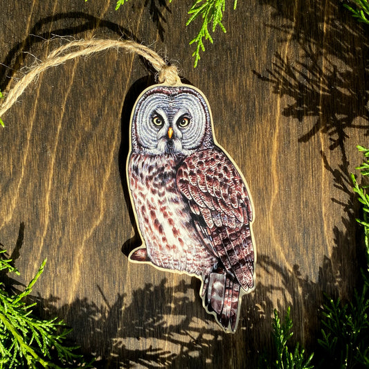 A wood print ornament featuring an illustration of a great gray owl