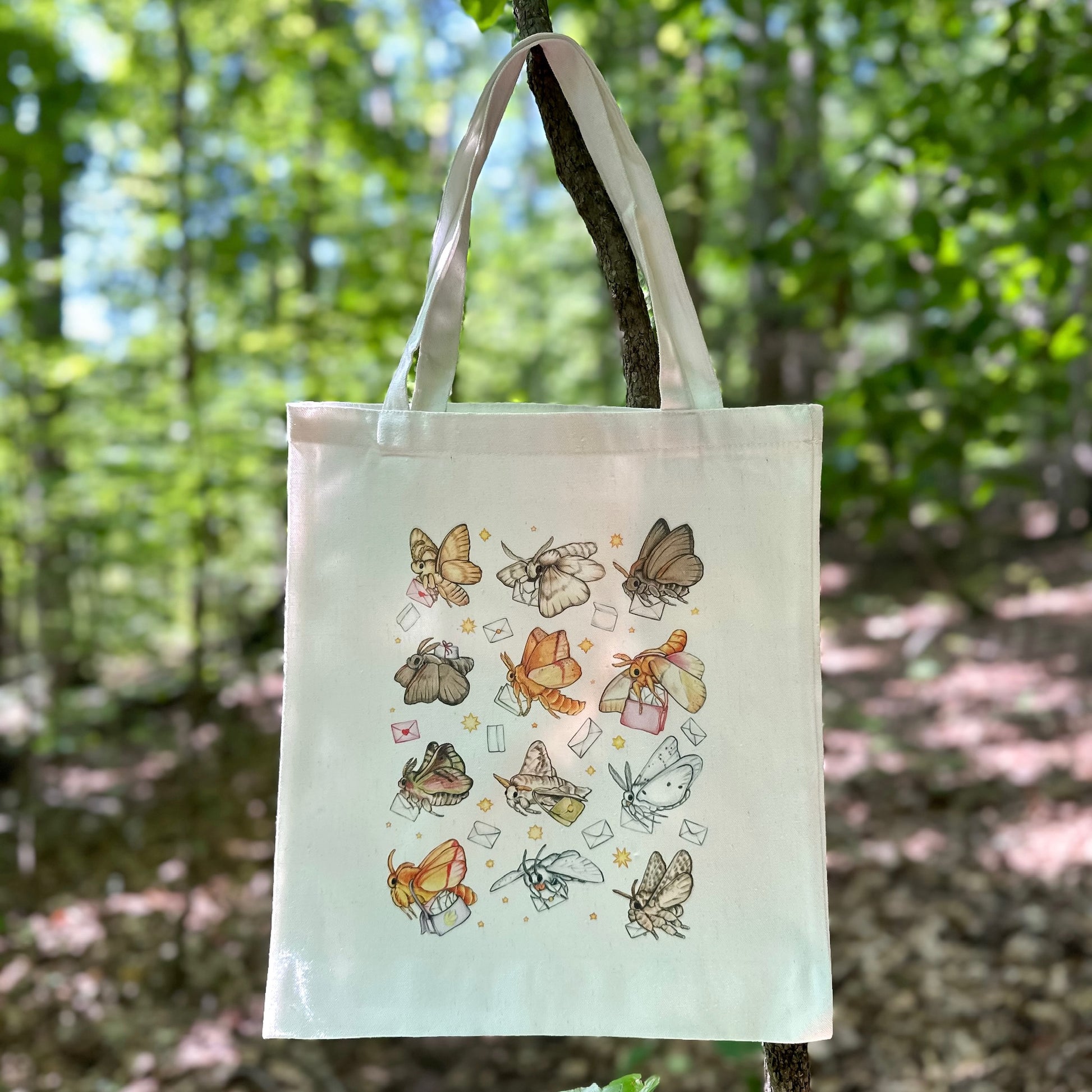 A tote bag featuring an illustration of moths delivering mail