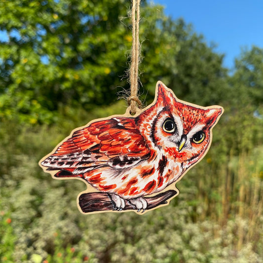 A wood ornament of a red morph eastern screech owl. 