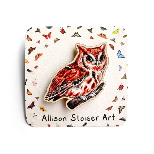 A hand holds a sustainably sourced wooden pin featuring an illustration of an eastern screech owl pin