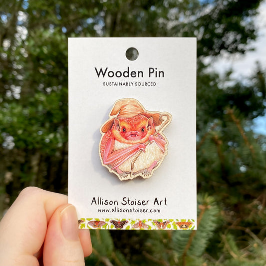 A wooden pin of an eastern red bat with a wizard hat and staff