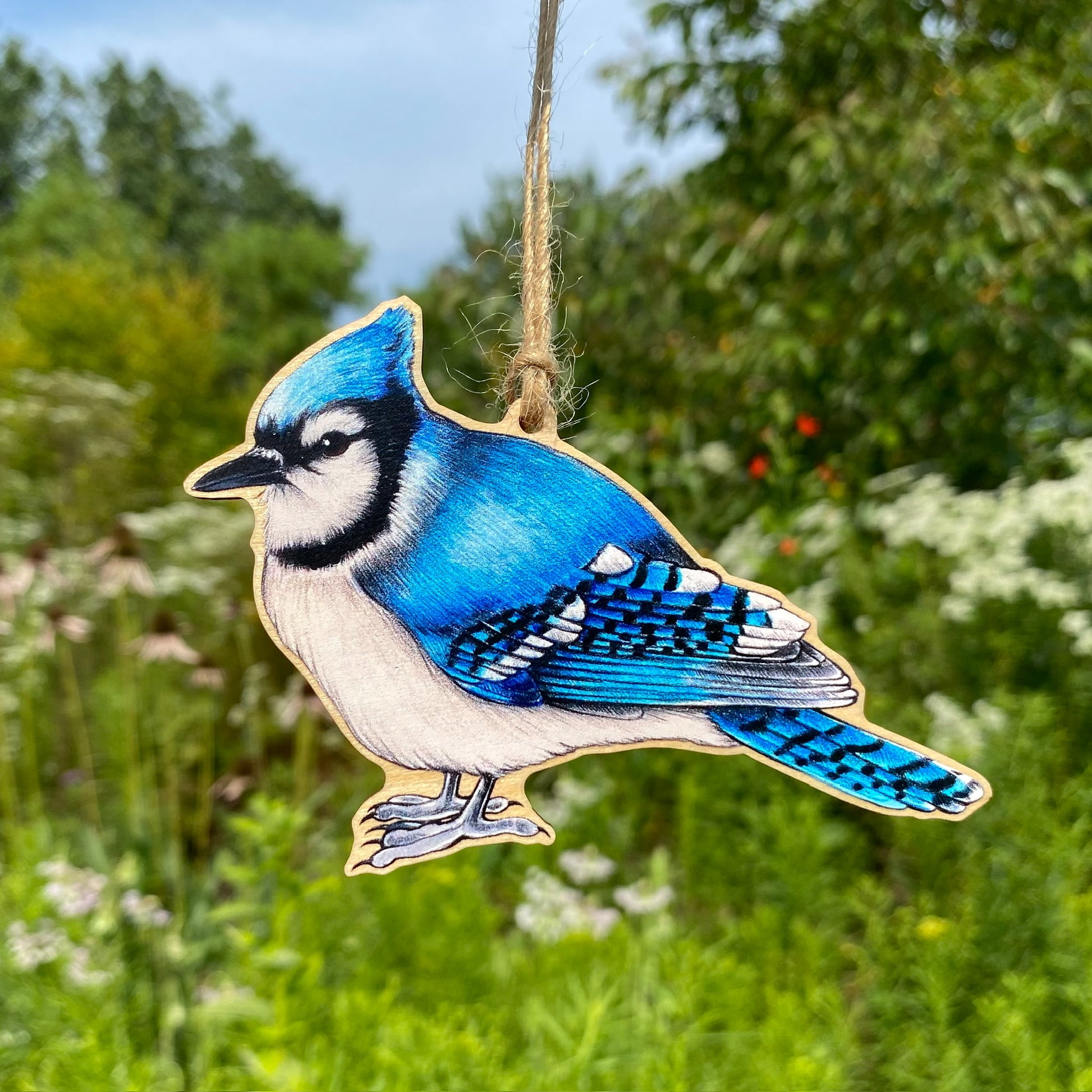 A wood print ornament featuring an illustration of a blue jay