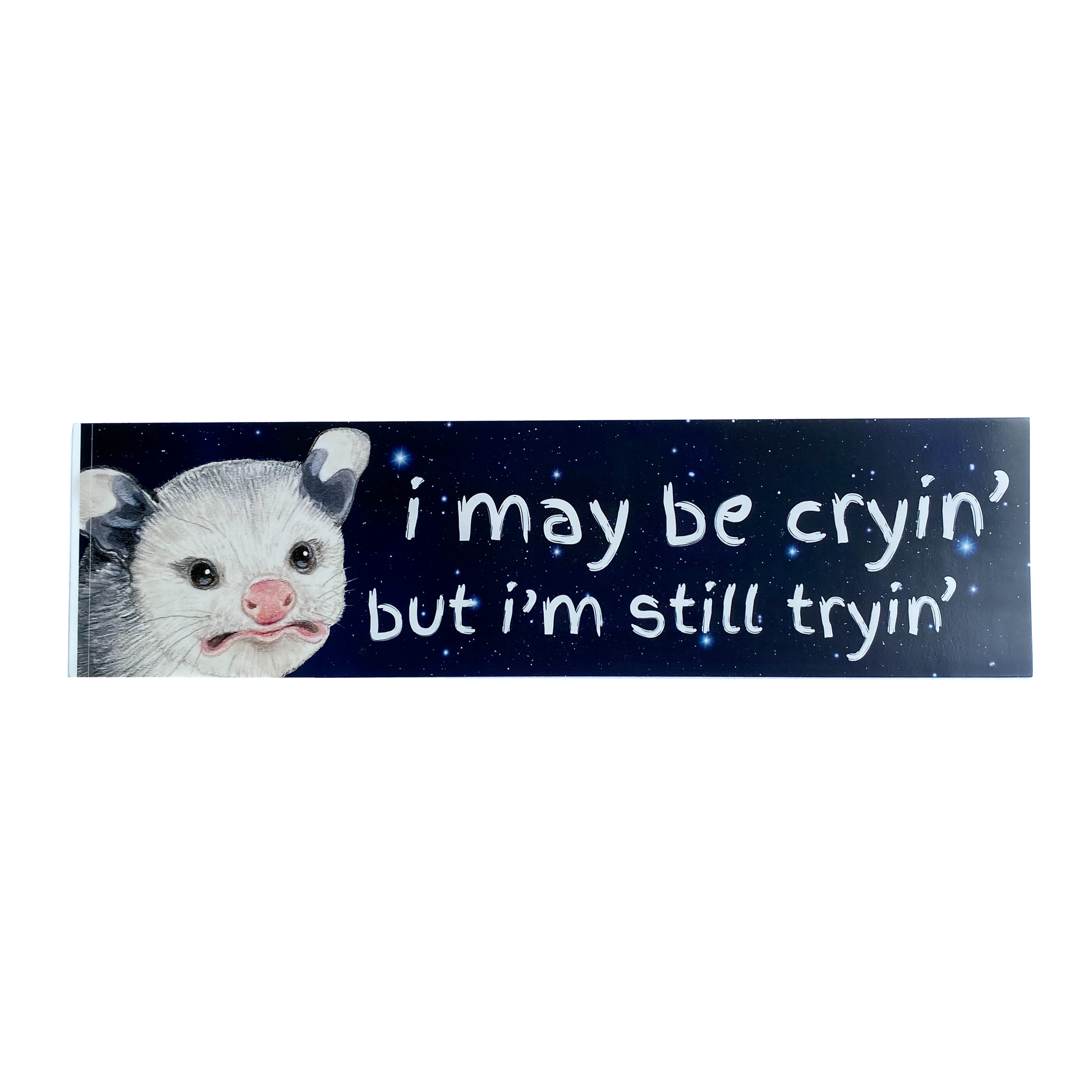 A bumper sticker featuring a baby opossum with text reading "I may be cryin' but I'm still tryin'" 