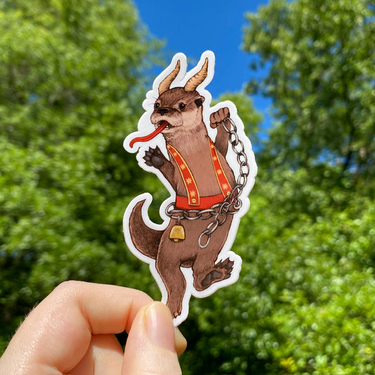 A hand holding a sticker of an otter dressed as Krampus