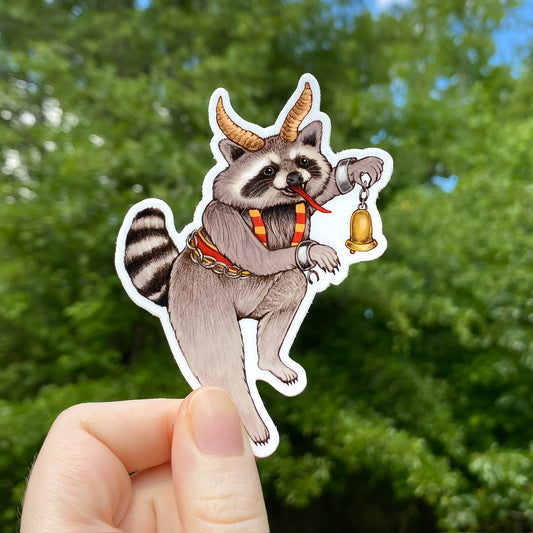 A hand holding a sticker of a raccoon dressed as Krampus