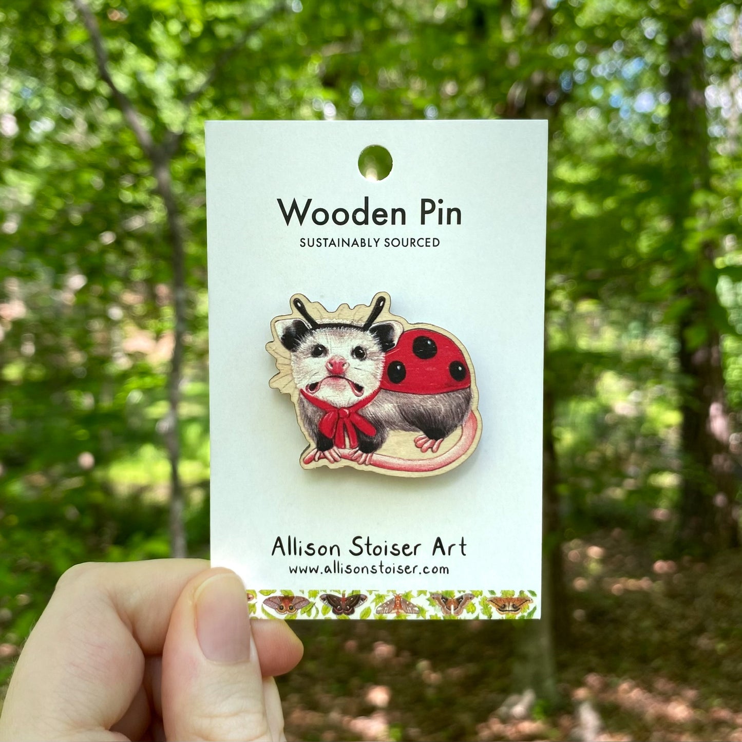 A wooden pin of an opossum dressed up as a ladybug