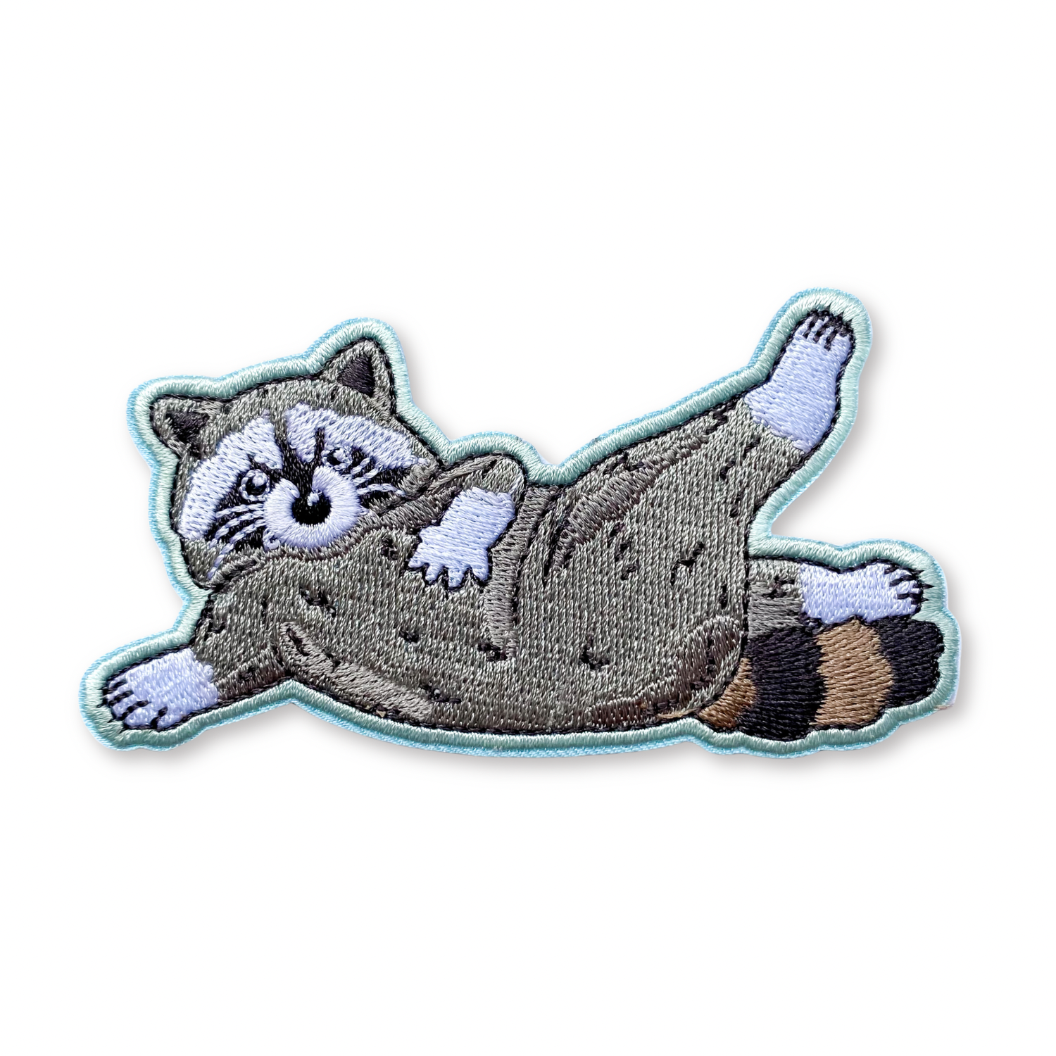 Embroidered patch of a lounging raccoon on a white background