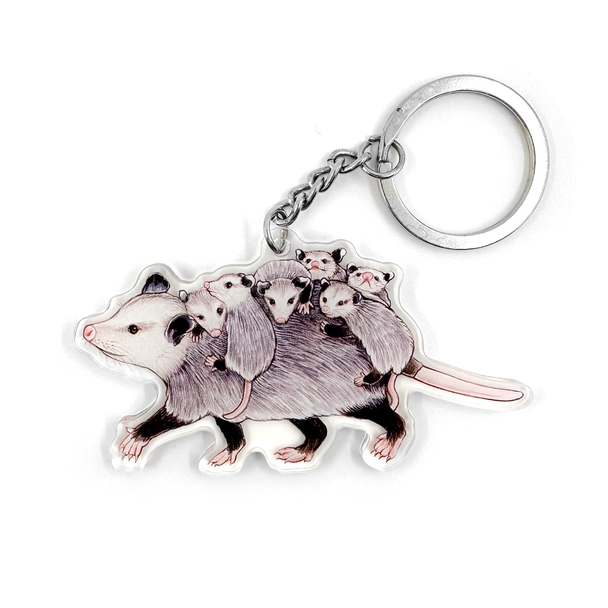 A keychain featuring an illustration of a mom opossum carrying babies on her back