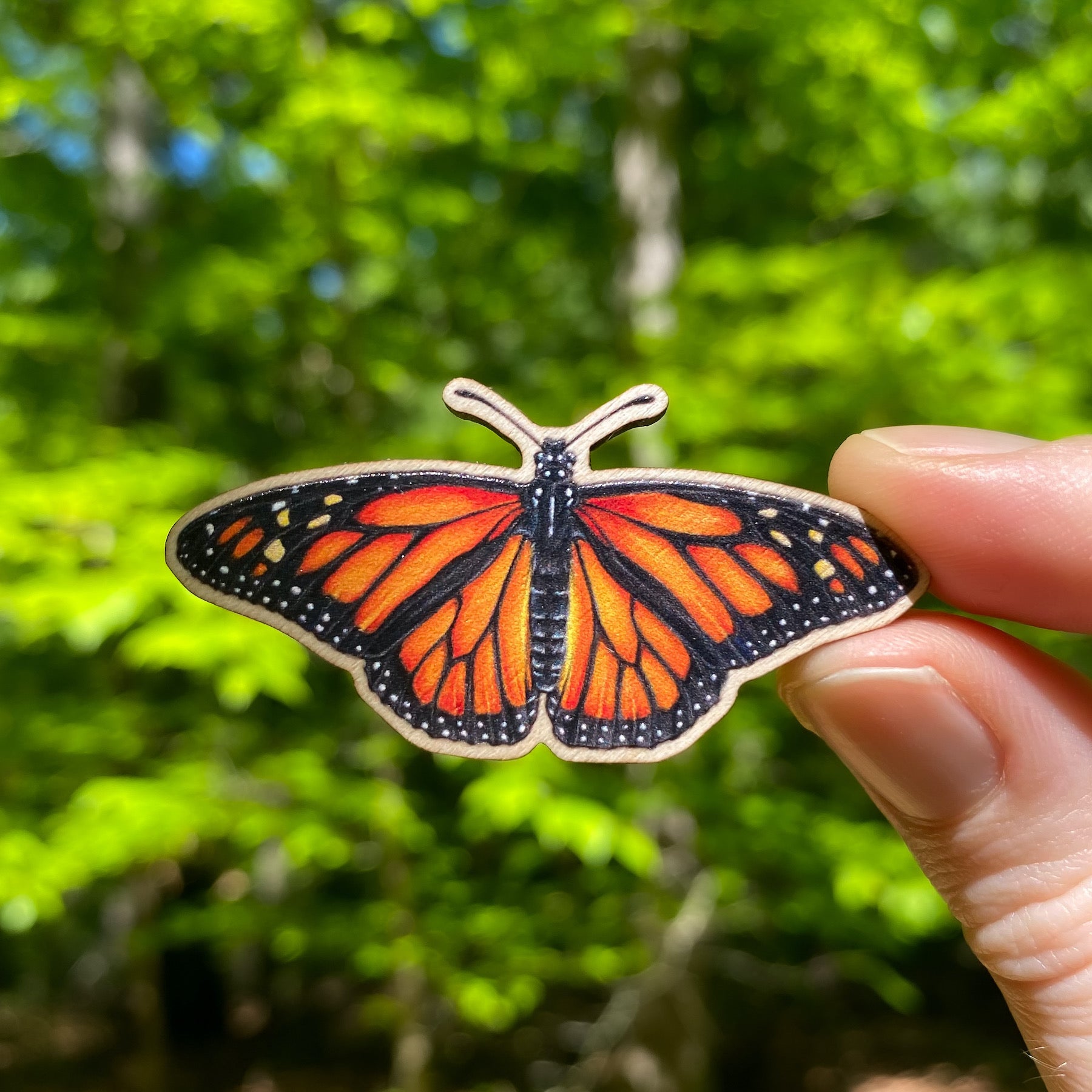 A sustainably sourced wooden pin featuring a monarch butterfly