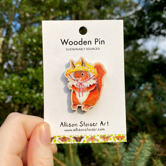 A wooden pin of a red squirrel in a mushroom hat