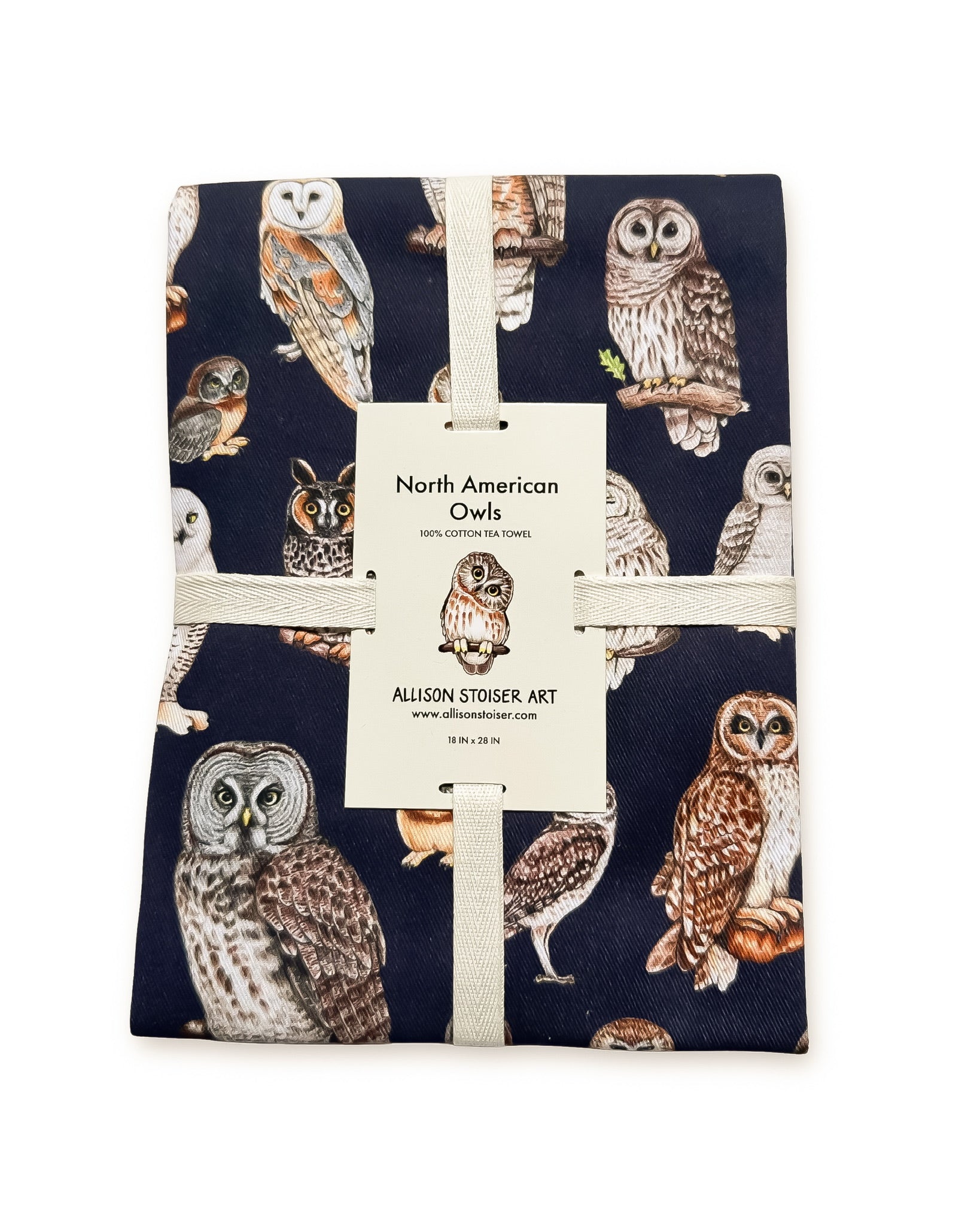 A tea towel featuring a detailed print of various North American Owls on a dark navy blue background. The fabric is wrapped with a white ribbon.