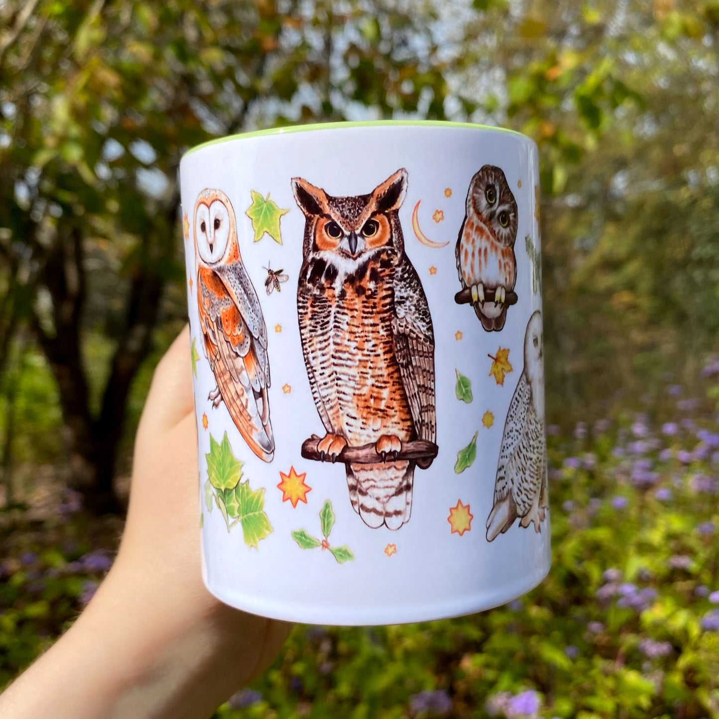 Ceramic mug with owl illustrations held in front of a natural background