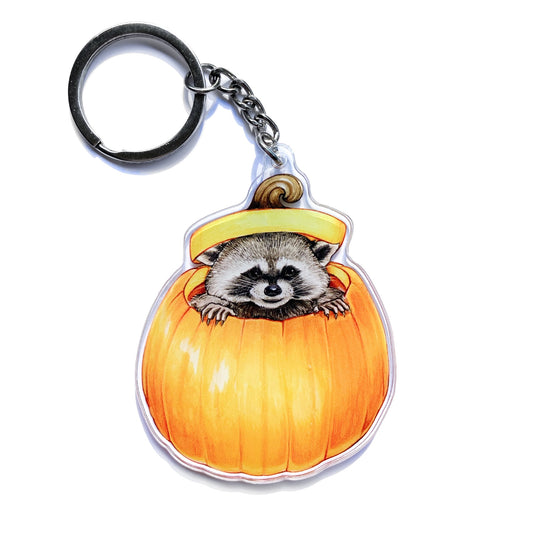 This double-sided acrylic keychain features my illustration of a raccoon peeking out of a pumpkin.&nbsp;