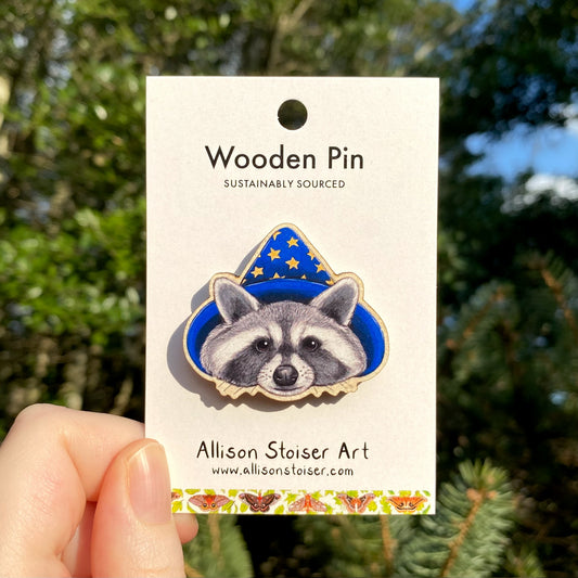 A wooden pin of a raccoon in a wizard hat