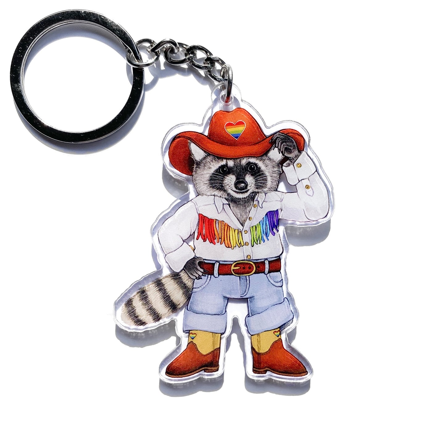 A keychain featuring an illustrated raccoon dressed as a cowboy with a rainbow-fringed shirt