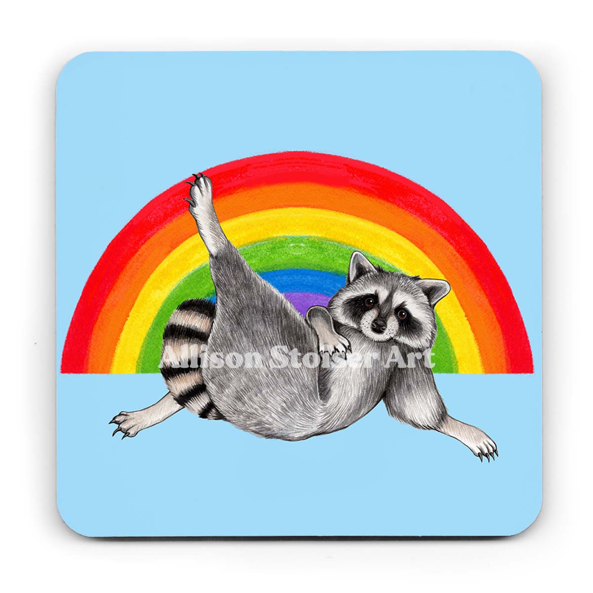 A light blue coaster of a raccoon lounging in front of a rainbow on a white background.