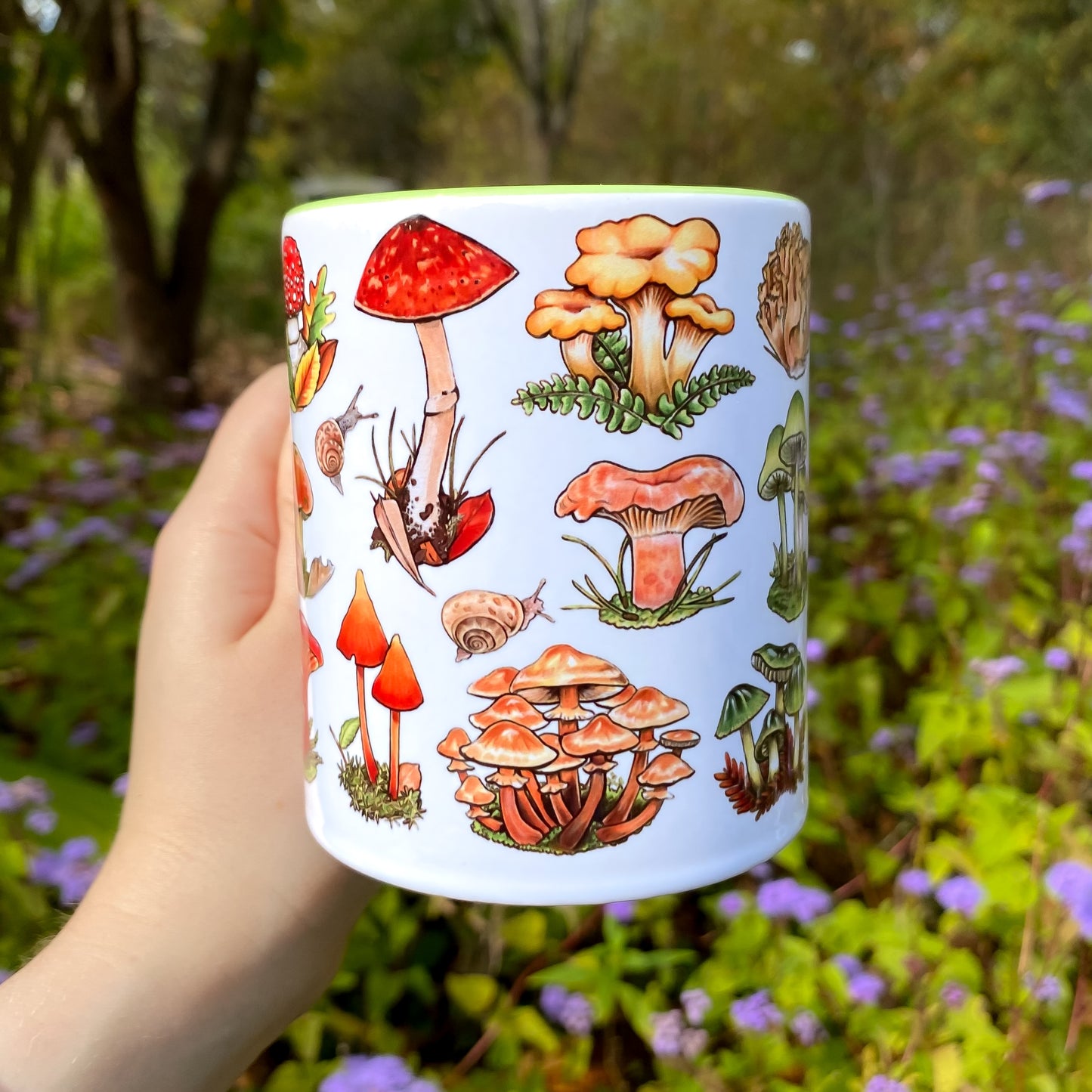 Ceramic mug with mushroom illustrations held in a hand against a natural background