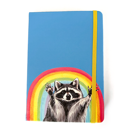Notebook with a raccoon and rainbow on a blue background