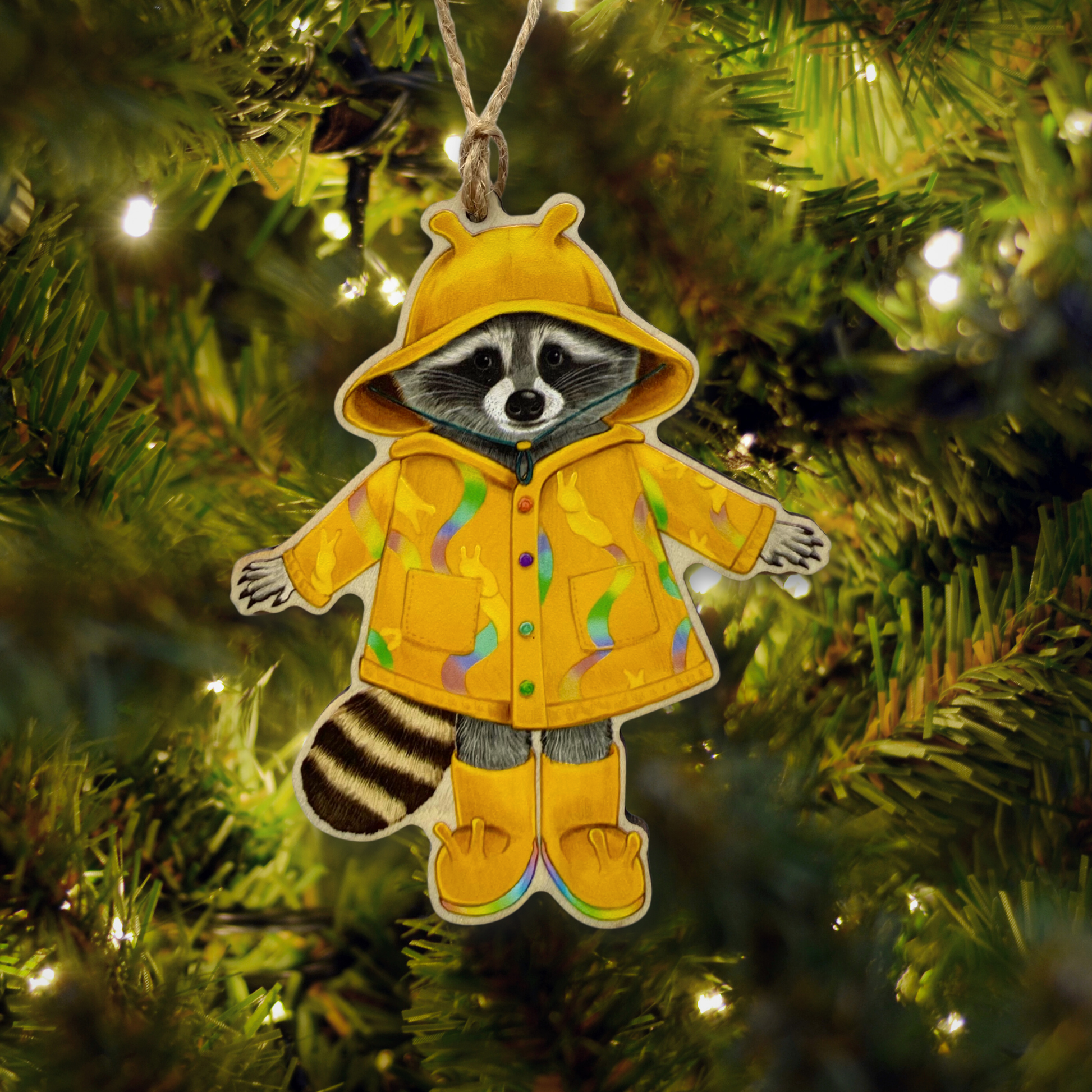 Decorative ornament of a raccoon in a yellow raincoat hanging on a Christmas tree.