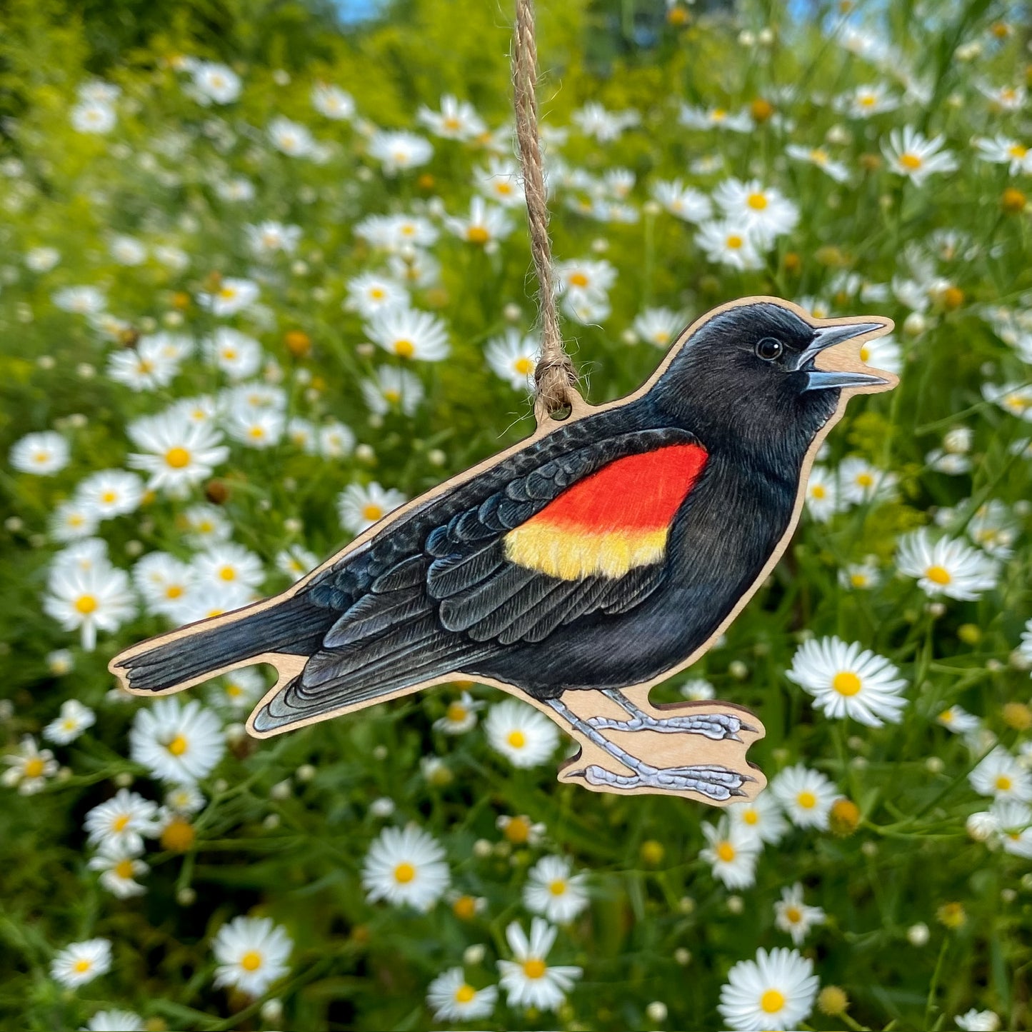 Red-winged blackbird ornament hanging among white flowers.