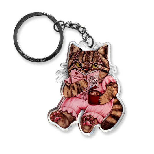 A keychain of a cat reading a romance book.