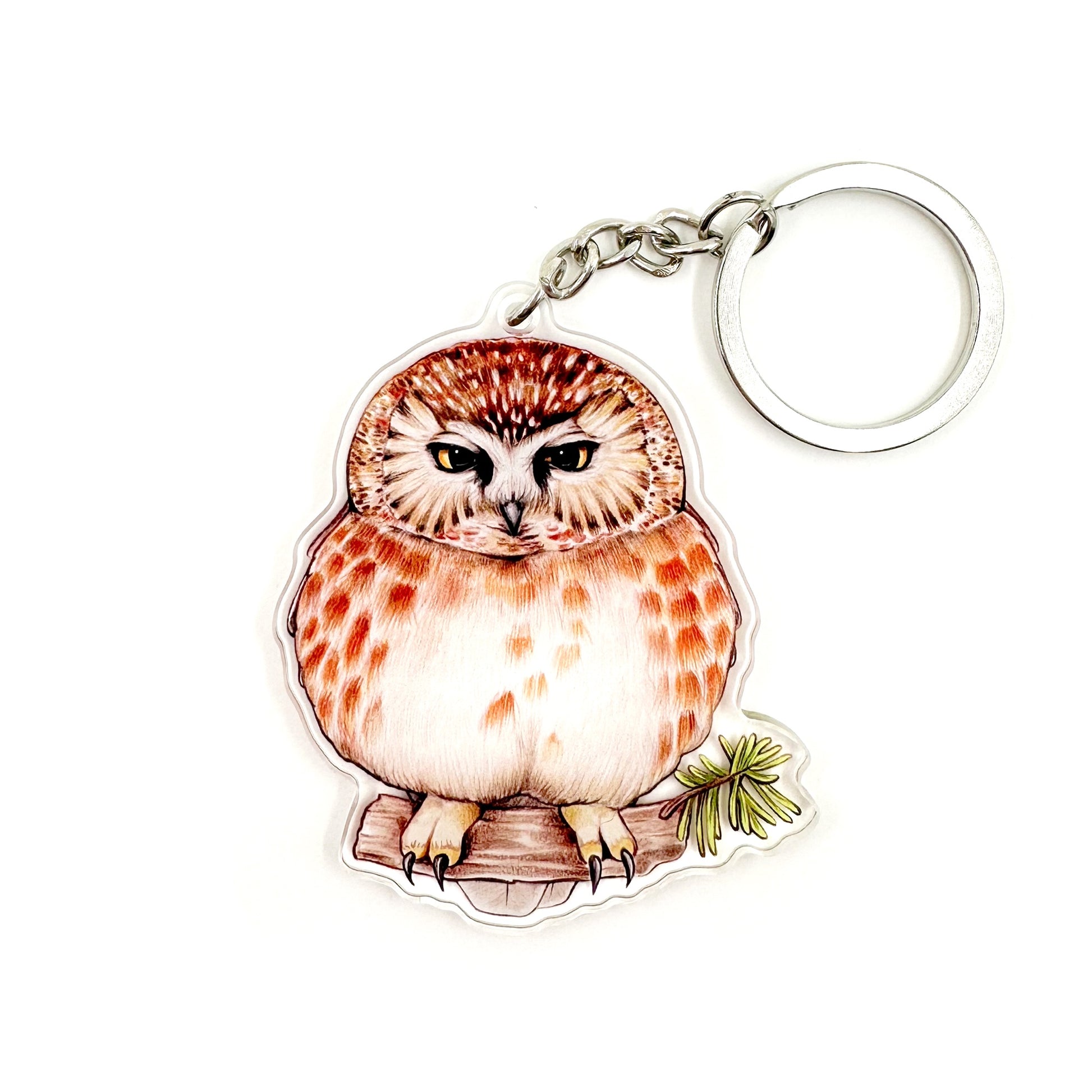 A keychain featuring an illustration of a grumpy saw whet owl