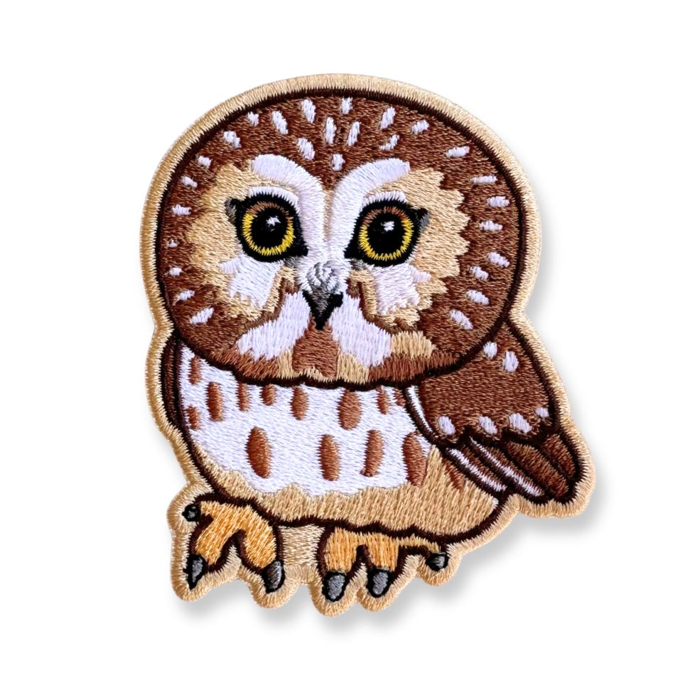 Embroidered patch of a saw-whet owl on a white background.