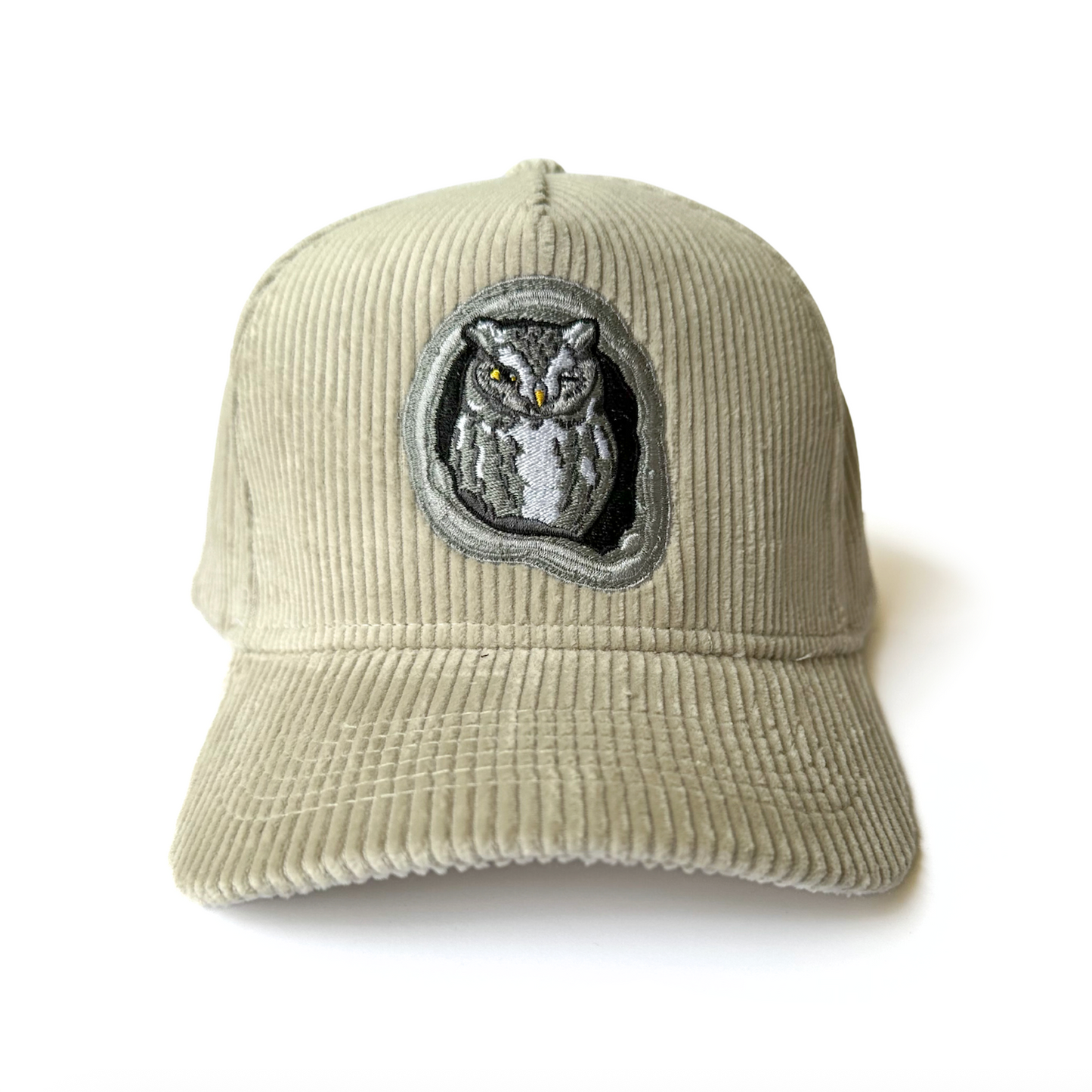 Beige corduroy cap with an embroidered screech owl on a white background