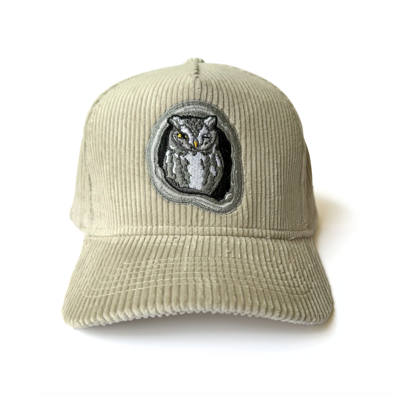 Beige corduroy cap with an embroidered screech owl on a white background