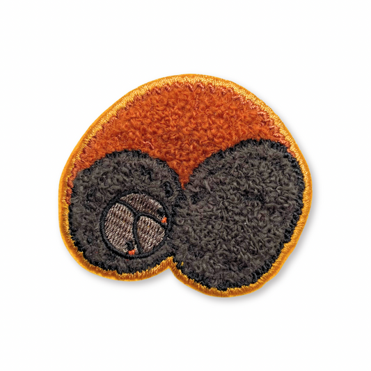 Chenille patch of a curled up woolly bear on a white background