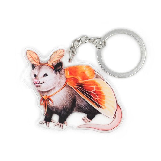 A keychain featuring an illustration of an opossum dressed as a flannel moth