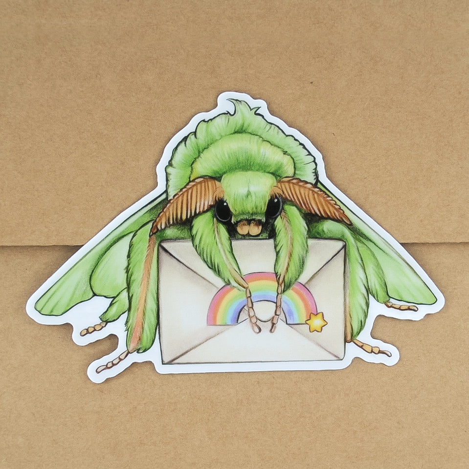 A weatherproof vinyl sticker of a green moth holding a letter with a rainbow sticker on top of a Kraft envelope.