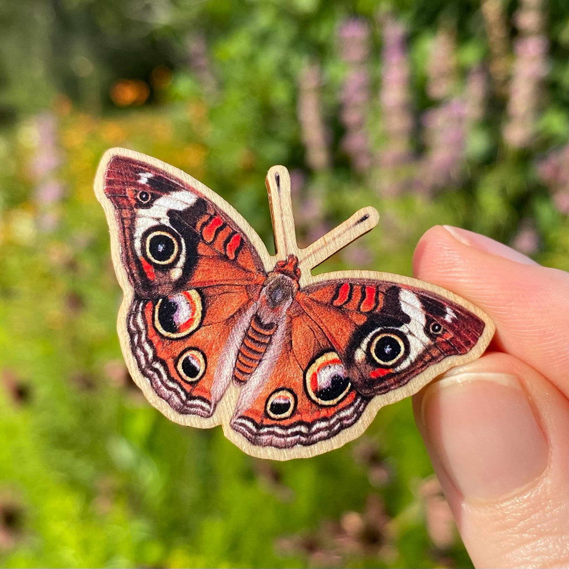 A sustainably sourced wooden pin featuring a common buckeye