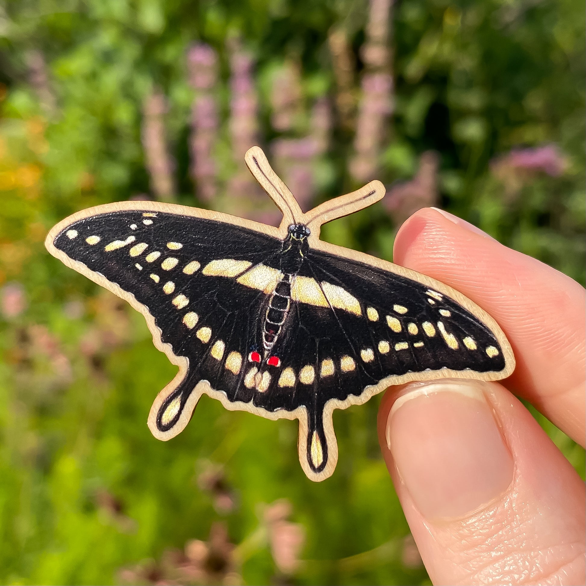 A sustainably sourced wooden pin featuring a giant swallowtail