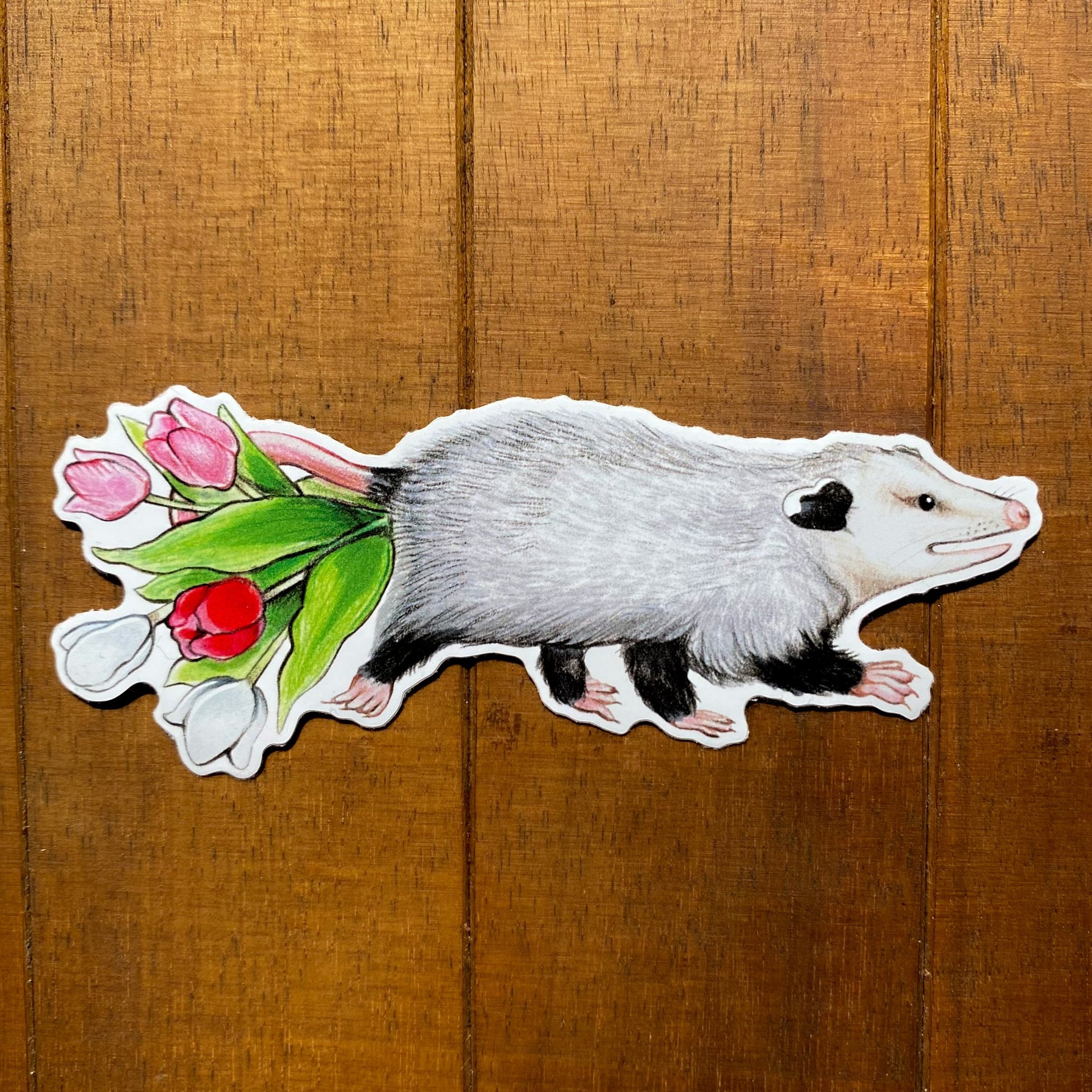 A weatherproof vinyl sticker featuring an illustration of an opossum carrying tulips in its tail