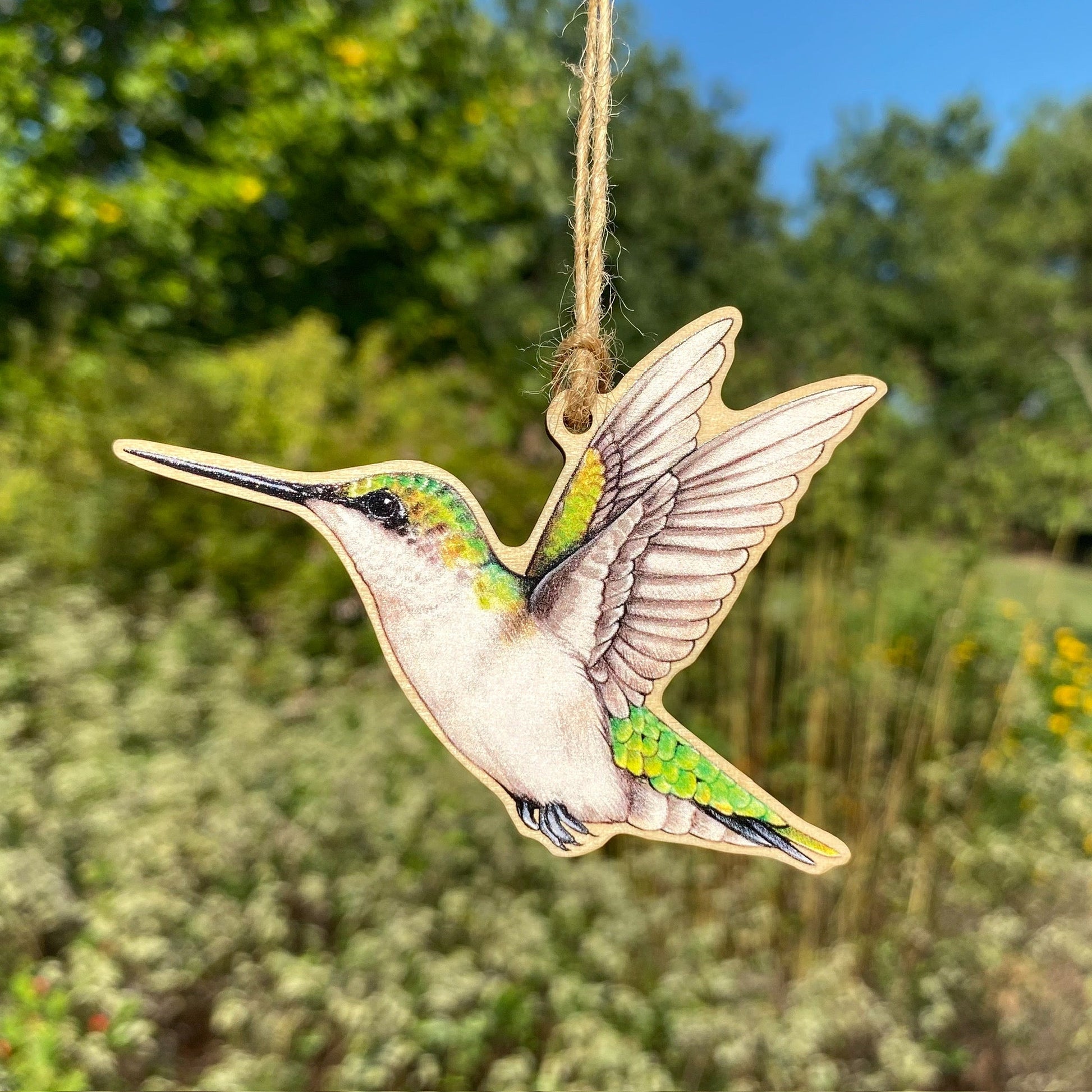 A wooden ornament strung with twine of a female ruby-throated hummingbird.