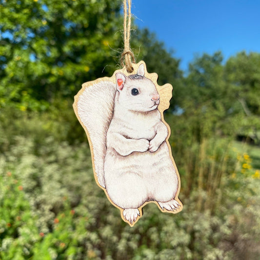 A wooden ornament strung with twine of a white squirrel.