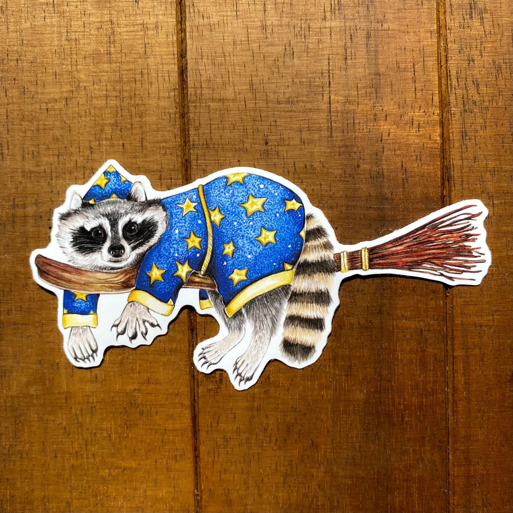 A sticker featuring an illustration of a raccoon wizard