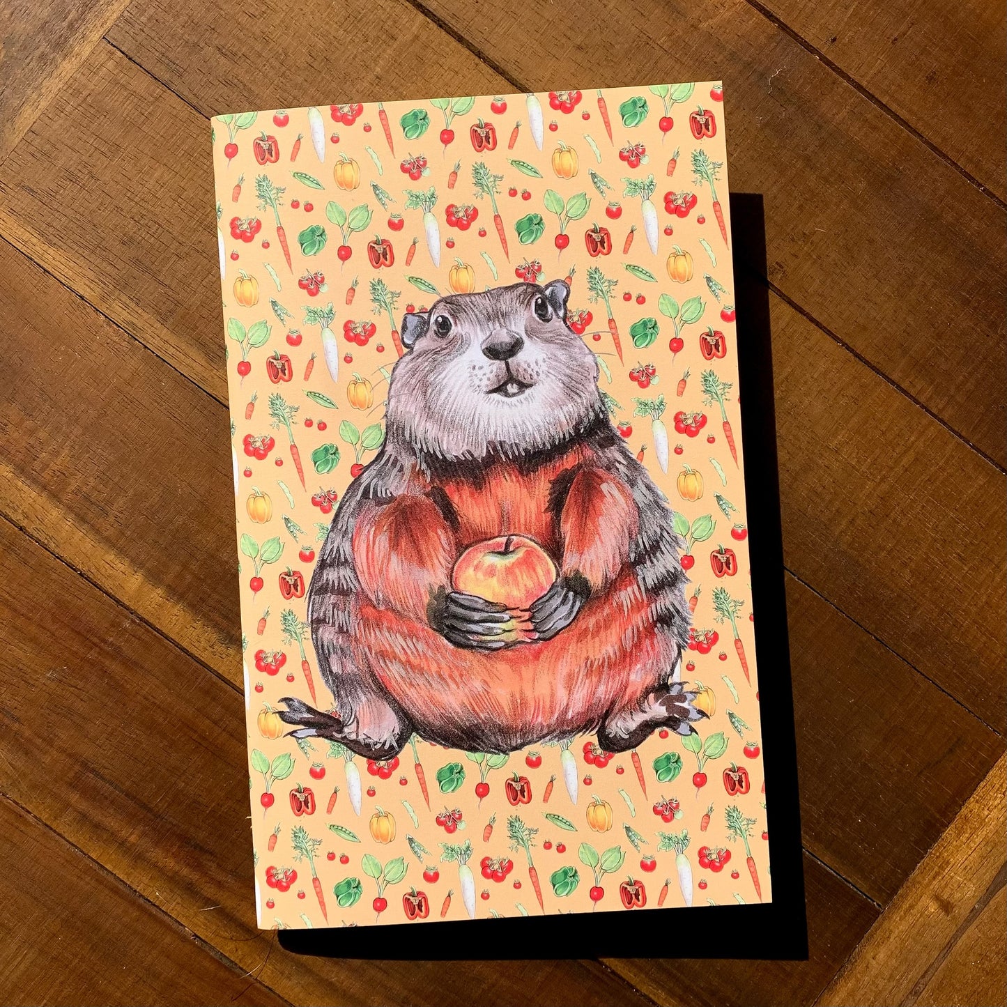 A handmade journal featuring a groundhog and a pattern of garden veggies on a yellow  background